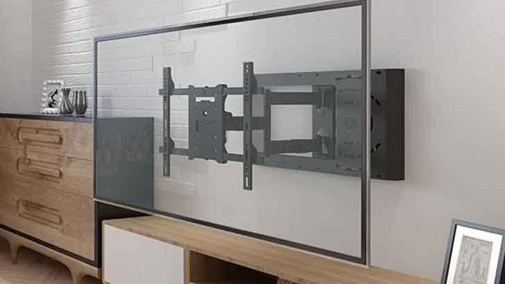 A technician from DC Metro IT Help installing a TV on a wall mount in a modern office space.
