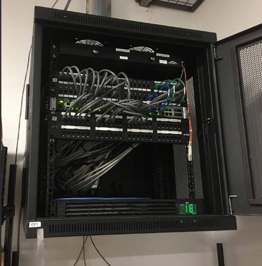 Inside view of IDF 11 network cabinet with patch panels, Ethernet cabling, and switch hardware used in diagnosing a store's intermittent internet issue.