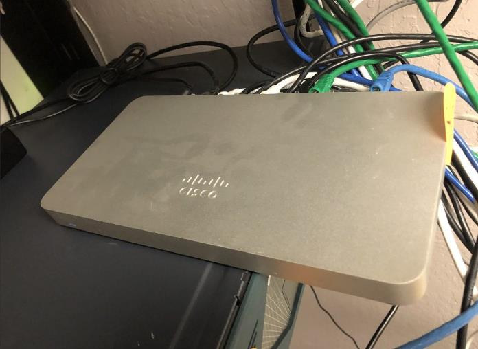 Cisco Meraki MX68 security appliance connected to multiple Ethernet cables on a store’s POS desk.